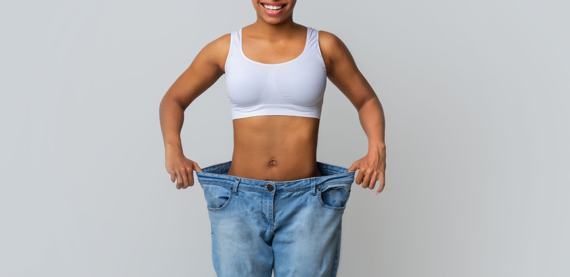Happy young woman with too large jeans weight loss